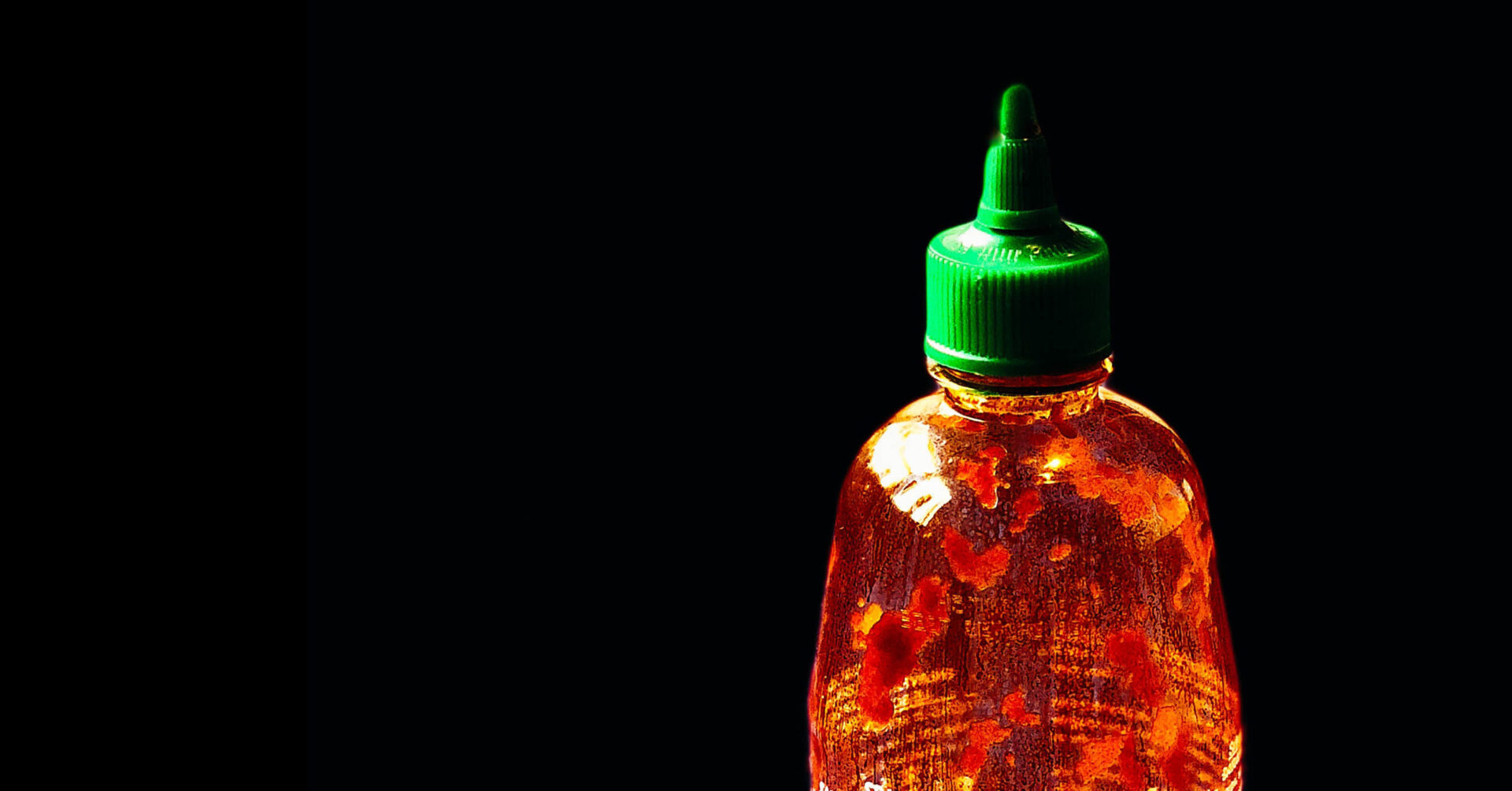Bottle of Huy Fong Sriracha on a table.