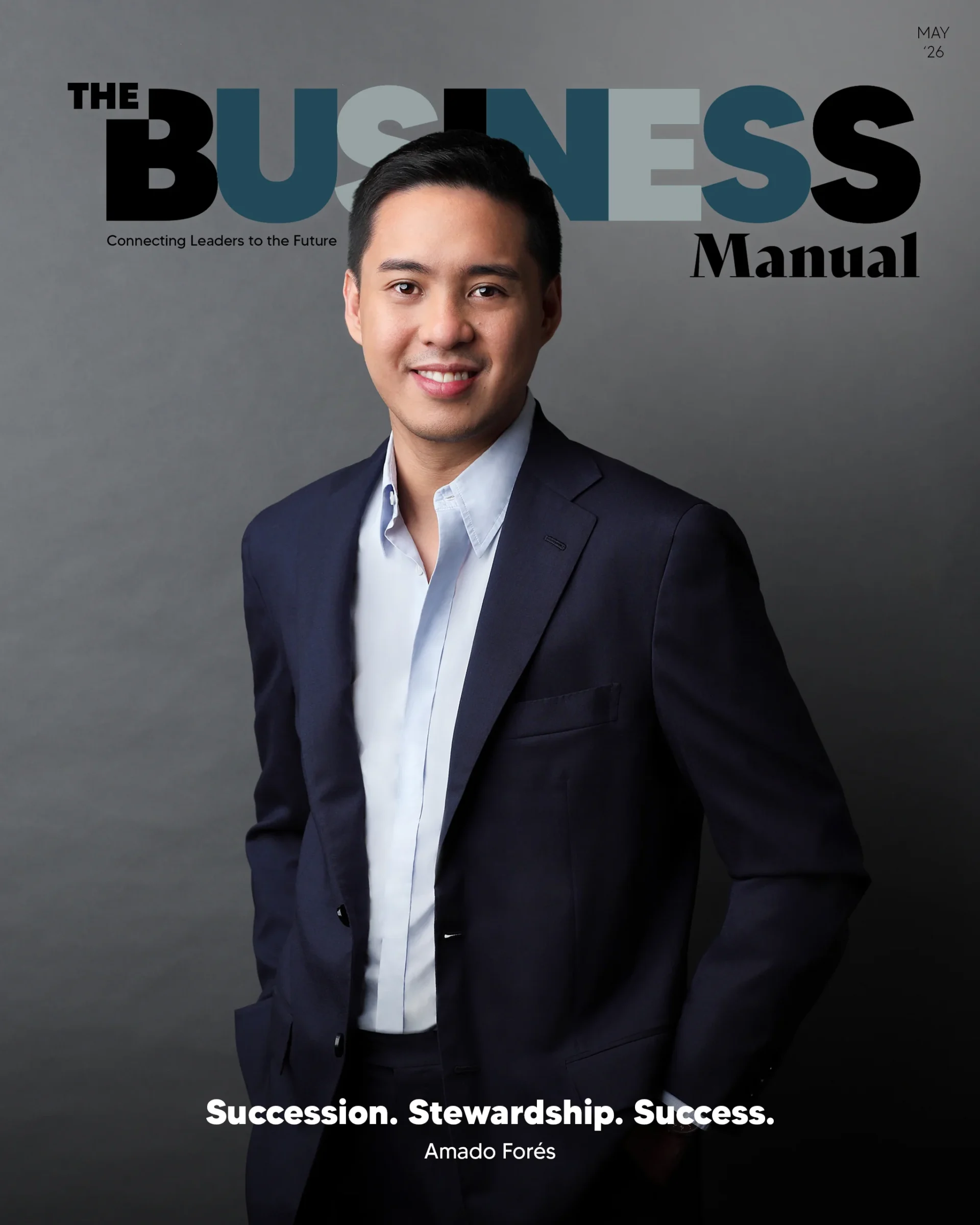 Portrait of a man in a navy suit and light blue shirt, looking to the right against a gray studio backdrop.